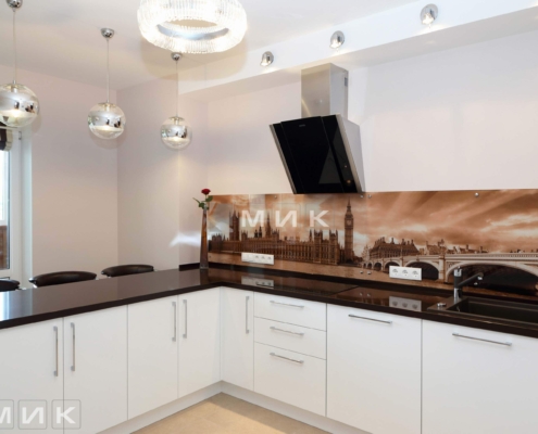 Дизайнерська кухня MIK з елементами міської тематики та сучасним освітленням Біла глянсова кухня із зображенням Лондона на фартуху та сучасними світильниками