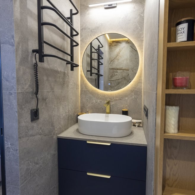 Синя тумба та кругле дзеркало в санвузлі на замовлення